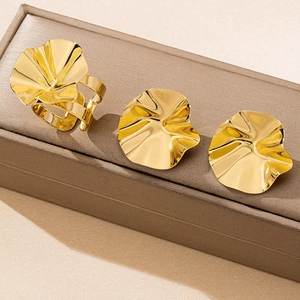 Detail view of gold wavy abstract leaf ring and stud earrings set on a jewelry box