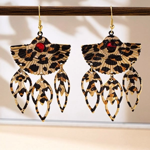 Close-up of leopard print fan-shaped drop earrings with red stone on wood stand