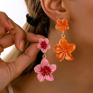 Detail of pink and orange flower drop earrings with golden edges shown on a model