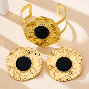 Detail of vintage gold hammered metal jewelry set with black enamel inlay and earrings