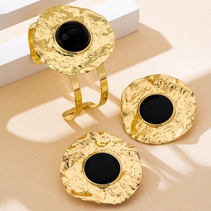 Detail view of gold hammer-textured cuff bracelet and earrings set with black stones