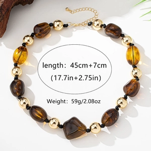 Boho-Perlenkette mit braunen Harzperlen und goldenen Kugeln auf einem warmen Hintergrund