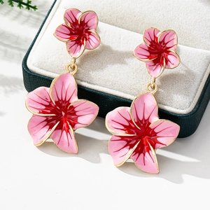 Macro shot of pink enamel floral earrings with gold accents on a white jewelry box lining