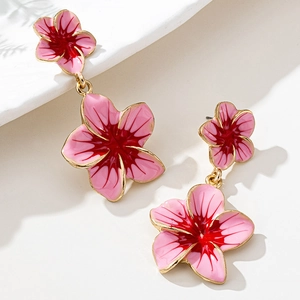 Detailed close-up of pink camellia floral drop earrings with hollow geometric gold frame