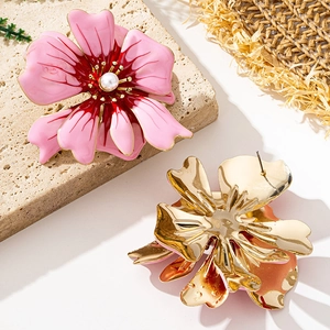 Detail of pink enamel flower earrings with central white pearl and gold metal backing