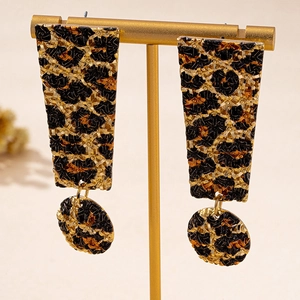 Detail view of leopard print drop earrings on a gold stand featuring square and round shapes
