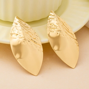 Orecchini a foglia dorata con trama martellata e finitura liscia su piatto in ceramica