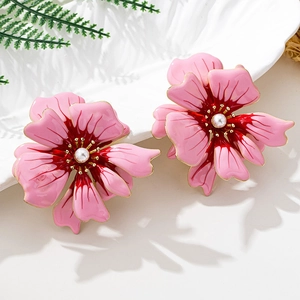 Detail of pink camellia earrings with pearl center and golden edges on floral tray