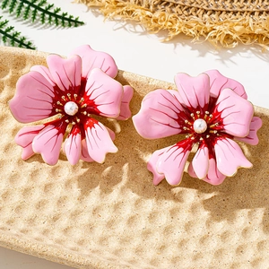 Close-up of pink camellia floral stud earrings with gold trim and white pearl center