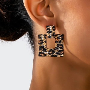 Detailed close-up of geometric square earrings featuring leopard print and small rhinestones