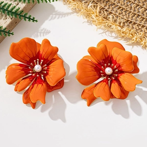 Close-up of large orange gradient flower earrings with central pearl on stone
