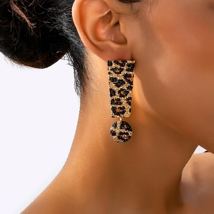 Close-up of leopard print exclamation mark drop earrings worn on a woman's ear