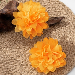 Detailansicht lebhafter orangefarbener Stoffblumen-Ohrringe auf rustikalem Grund