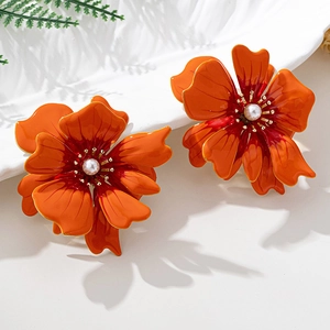 Detailed view of large orange camellia earrings with central pearl and gold alloy edging
