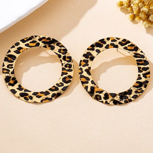 Macro detail of large gold-tone round hoop earrings with leopard print and hammered texture