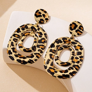 Macro shot of triple-layered oval leopard print earrings with gold trim on a stone stand