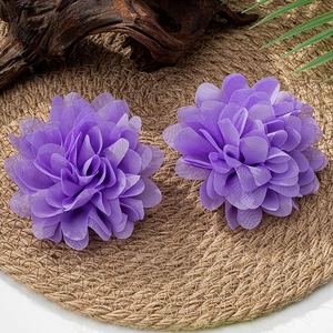 Makroaufnahme lila Chiffon-Blumenohrringe auf Webmatte mit natürlicher Dekoration