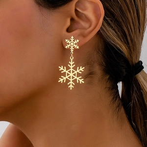 Detailed view of elegant double-layered golden snowflake drop earrings worn by a model