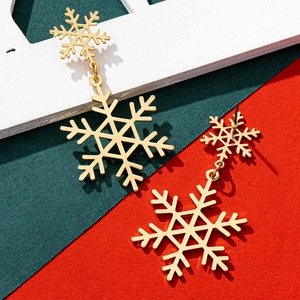 Detailed close-up of golden snowflake drop earrings on a festive Christmas background