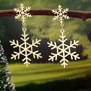 Detailed view of gold snowflake drop earrings hanging on a natural tree branch