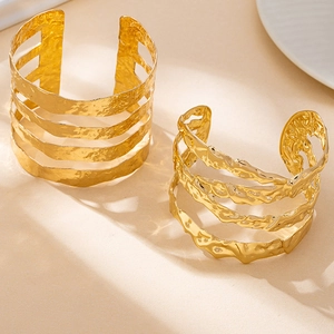 Dettaglio di bracciale dorato irregolare con trama martellata e design a lava fluida