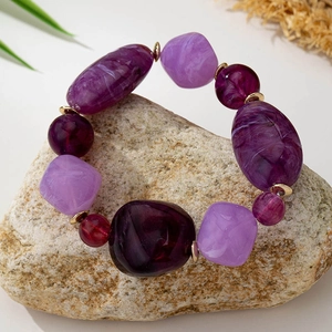Detail of purple beaded bracelet with mixed marble textures and golden spacers on stone