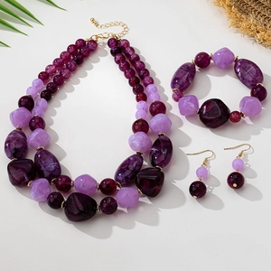 Macro detail of purple marbled resin bead necklace and gold plated jewelry set components