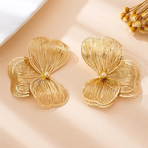Detailansicht großer goldener Blumenohrringe mit gebürsteter Textur und zentraler Metallperle