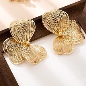 Detailaufnahme von goldenen Filigran-Blumenohrringen mit strahlenden Metallblättern