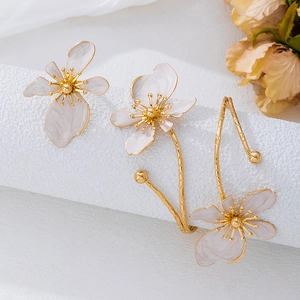 Detailed close-up of golden floral earrings and ring set with pearlized flower petals