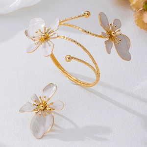 Detailed macro view of gold-plated flower ring and spiral bracelet with marble texture