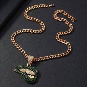 Macro-opname van groene strass lippen hanger aan een gouden Cubaanse schakelketting