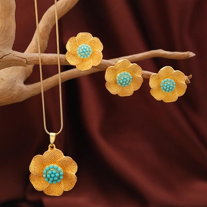Vintage Blumen-Schmuckset aus Goldlegierung mit blauen Perlen auf Holz-Hintergrund
