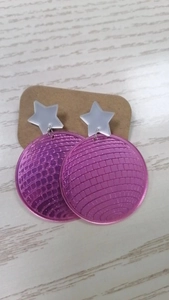 Detail of pink disco ball earrings with white star top on acrylic jewelry display