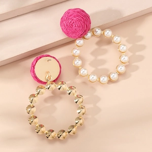 Detail of pink raffia stud earrings with pearl bead hoop and textured golden ring