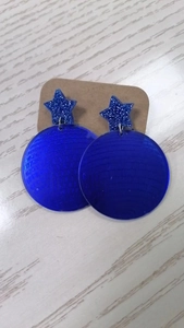 Detail of blue glitter star earrings with textured laser round disc on card