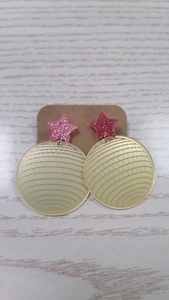Detailed view of pink star and yellow disco ball acrylic earrings on a display card