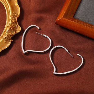 Detailopname van zilveren hartvormige oorringen op een vintage getextureerde stoffen achtergrond