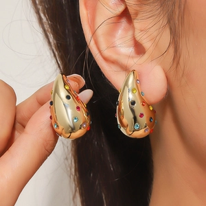 Pendientes de gota dorados con cristales coloridos en una modelo para un estilo punk