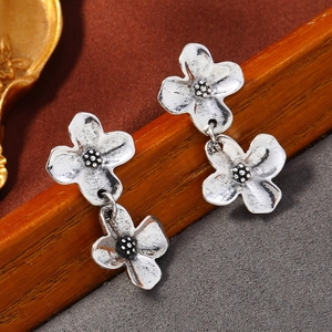 Detail van vintage zilveren bloemoorbellen met antieke afwerking en dubbel bloemmotief