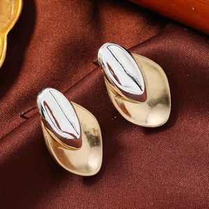 Macro detail van asymmetrische zilveren ovaal en gouden basis op elegante kwastje oorbellen