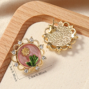 Detailed macro view of retro floral relief earrings with pink enamel and crystals