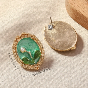 Detail view of retro oil painting style earrings with green enamel and pearl inlay
