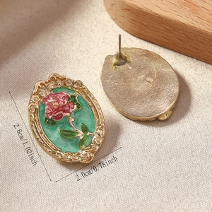 Detail view of retro flower earrings with pink roses and emerald enamel finish