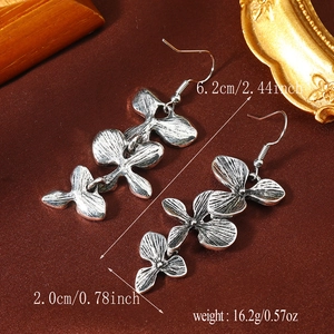 Detalle de pendientes de flor plateados con medidas 6,2 cm y peso 16,2 g sobre tela de seda