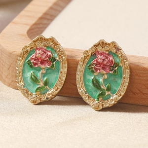 Vintage gold-plated oval earrings with red rose oil-dripping art on a wooden tray