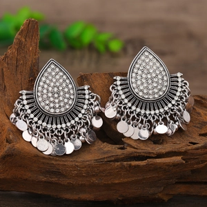 Primer plano de pendientes boho plateados con pedrería y lentejuelas metálicas