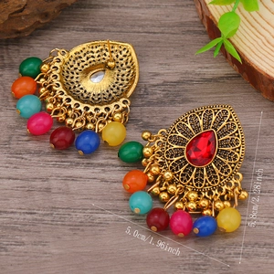 Detalle de pendientes vintage étnicos con gema roja y cuentas de colores