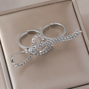 Nahaufnahme von silbernem Doppelfingerring mit Strasssteinen auf goldener Schmuckbox