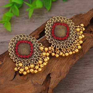 Detalle de pendientes Jhumka vintage con pedrería roja y flecos de cuentas doradas